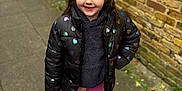 Paige-madison is registered to the contest to win money with this photo: child, girl, smile, outdoor, sidewalk, brick_wall, jacket, hearts_pattern, leggings, boots, casual_clothing, happy, portrait, person, standing, urban, daylight, fashion, winter_wear, cute