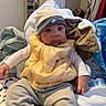 Rakai joined the competition — help win amazing prizes! baby, child, infant, yellow_vest, hat, nike, blanket, clothing, indoors, bed, pile, comfort, cute, portrait, face, wide_eyes, sitting, warm, room, casual
