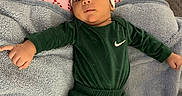 Rakai is registered to the contest to win money with this photo: baby, infant, child, green_clothing, nike, headband, blanket, pillow, candy_cane_pattern, hand, finger, lying_down, indoors, cute, cozy, soft_texture, person, portrait, young_child, sleepwear