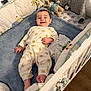 Eli is registered to the contest to win money with this photo: baby, blanket, child, comfort, crib, cushion, cute, floor, furniture, happy, indoor, infant, lying_down, pajamas, sleepwear, smiling, soft, stuffed_animal, toy, wood