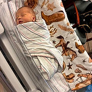 Tatum is registered to the contest to win money with this photo: newborn, baby, sleeping, infant, face, portrait, hospital, bassinet, blanket, swaddled, indoors, nursery, medical, crib, peaceful, cowboy_blanket, stars, patterned_fabric, chair, resting