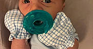 Tatum joined the competition — help win amazing prizes! baby, infant, child, portrait, pacifier, blue_pacifier, bib, checkered_bib, blue_clothing, lying_down, indoors, bed, pillow, close_up, face, eyes, wide_eyed, baby_clothing, cozy, photograph