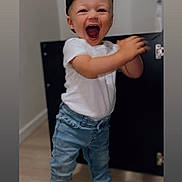 Alessio a rejoint le concours — aidez-le/la à gagner de superbes lots ! toddler, child, cap, black_cap, white_tshirt, jeans, denim, clapping, joyful, indoor, wooden_floor, cabinet, black_cabinet, shoes, black_shoes, expression, happy, standing, person, portrait
