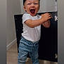 toddler, child, cap, black_cap, white_tshirt, jeans, denim, clapping, joyful, indoor, wooden_floor, cabinet, black_cabinet, shoes, black_shoes, expression, happy, standing, person, portrait