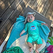 Tiziano participe au concours pour gagner de l'argent avec cette photo : baby, pacifier, hat, towel, sunbed, wooden_floor, feet, outdoor, clothing, child, relaxing, turquoise, babywear, summer, shade, person, infant, flooring, resting, cute