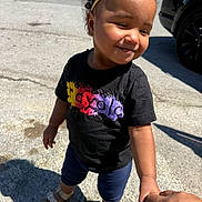 Kalea joined the competition — help win amazing prizes! toddler, child, holding_hand, yellow_headband, black_tshirt, colorful_print, sandals, outdoor, sunlight, shadow, pavement, car, smiling, curly_hair, person, happy, casual_clothing, daytime, skin, portrait