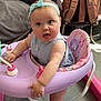 baby, child, headband, walker, pink, blue, indoor, floor, clothing, furniture, bag, curious, expression, feet, person, seat, toy, living_room, couch, folded_clothes