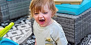 Benji is registered to the contest to win money with this photo: toddler, child, barefoot, outdoor, patio, toy, walker, furniture, cushion, plant, flower, grass, happy, playtime, pavement, clothing, shirt, pants, person, expression