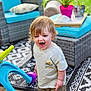 toddler, child, barefoot, outdoor, patio, toy, walker, furniture, cushion, plant, flower, grass, happy, playtime, pavement, clothing, shirt, pants, person, expression