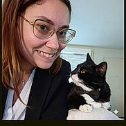 Praline a rejoint le concours — aidez-le/la à gagner de superbes lots ! woman, cat, tuxedo_cat, smiling, glasses, portrait, indoor, selfie, black_and_white_cat, bow_tie, pet, person, face, hair, clothing, window, couch, home, photography, animal