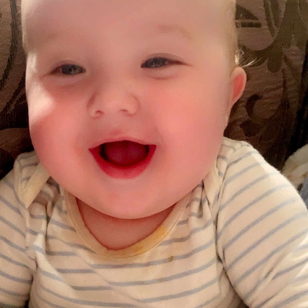 Alfie-Joe joined the competition — help win amazing prizes! baby, cheeks, child, closeup, cushion, cute, expression, face, hand, happy, indoor, infant, light, onesie, person, portrait, seated, smiling, striped_clothing, young