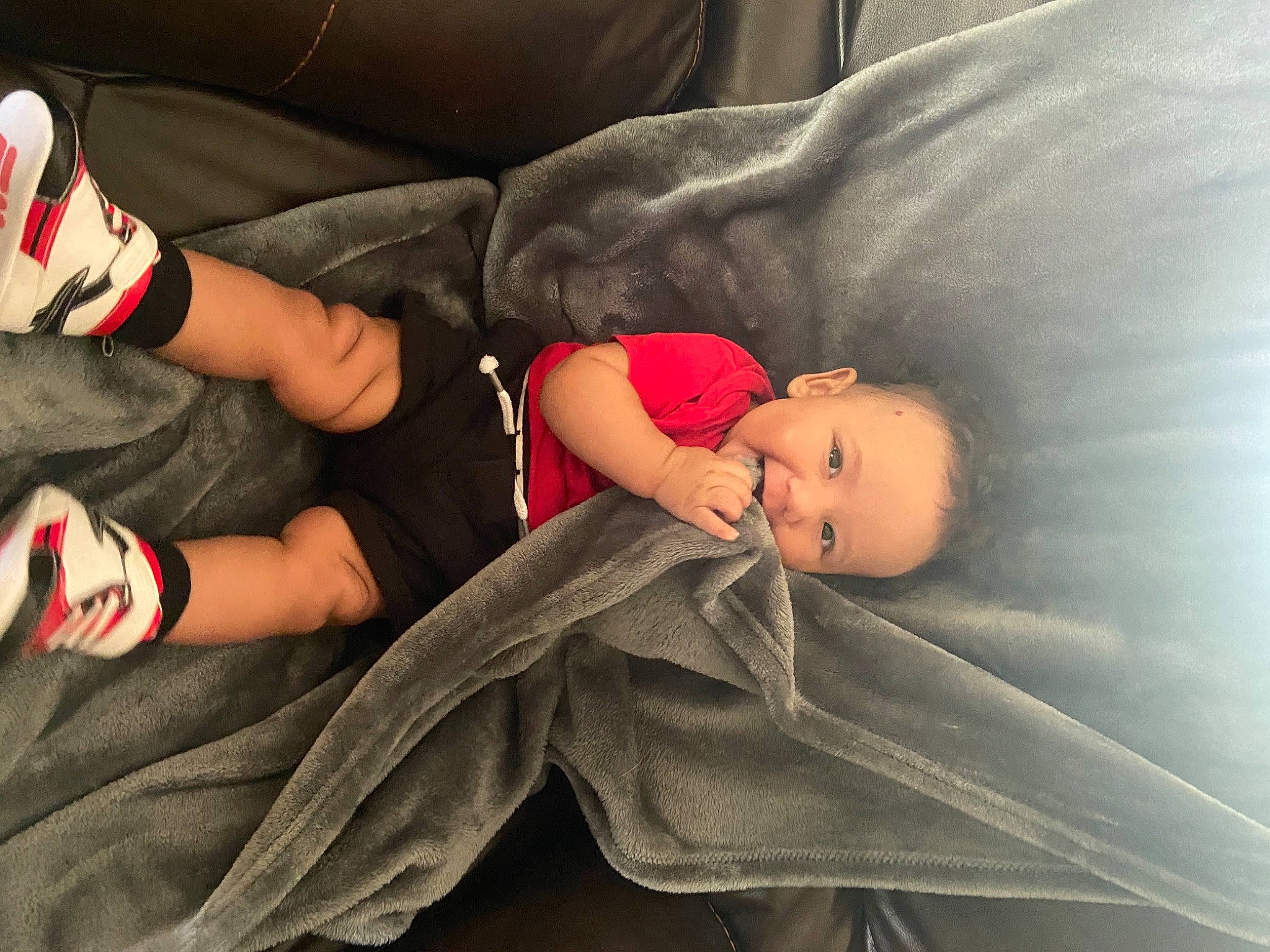 Marcel is registered to the contest to win money with this photo: arm, baby, baby_toddler_clothing, comfort, couch, finger, hand, head, human_body, human_leg, knee, leg, linens, person, sitting, skin, sock, textile, thigh, toddler