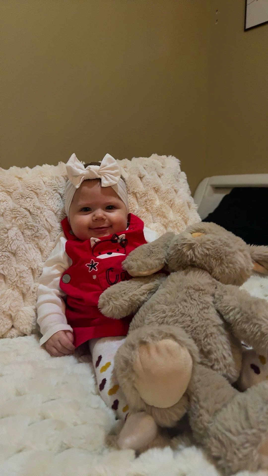 Vyctoire participe au concours pour gagner de l'argent avec cette photo : baby, bow, red_clothing, plush_toy, bunny, blanket, smiling, indoors, child, cute, soft_texture, cozy, sitting, person, headband, toy, happy, infant, warm, comfort
