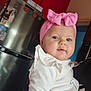 baby, child, pink_bow, headband, white_clothing, indoor, kitchen, fridge, red_wall, person, cute, portrait, holding, blue_eyes, infant, smile, toddler, cozy, home, face