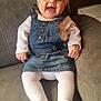 Vyctoire participe au concours pour gagner de l'argent avec cette photo : baby, child, smiling, denim, overall, headband, bow, white_tights, couch, indoor, happy, cute, portrait, sitting, clothing, person, infant, face, cozy, comfort