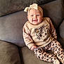 Vyctoire a rejoint le concours — aidez-le/la à gagner de superbes lots ! baby, smiling, headband, bow, leopard_print, sitting, couch, gray_couch, cute_outfit, infant, happy, child, indoor, plush, comfortable, clothing, patterned_pants, long_sleeve, portrait, young_child