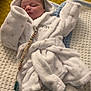 baby, sleeping, white_robe, booties, blanket, knitted_blanket, pacifier_clip, indoor, cozy, child, infant, soft, cute, peaceful, sleep, yellow_background, textured_background, clothing, person, resting
