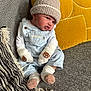 Archie joined the competition — help win amazing prizes! baby, infant, hat, mittens, bear_face, blue_overalls, white_shirt, couch, cushion, yellow_cushion, blanket, fringe, striped_blanket, knit_hat, soft_toys, sitting, indoor, cute, portrait, child