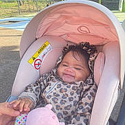 Mélina a rejoint le concours — aidez-le/la à gagner de superbes lots ! baby, car_seat, leopard_print, jacket, toy, pink, smiling, child, outdoor, playground, sunlight, hand, person, infant, cute, seat, hood, comfort, happy, young