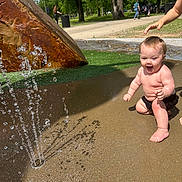 Kayyson joined the competition — help win amazing prizes! baby, child, toddler, water_fountain, splash, outdoor, park, grass, concrete, play, summer, sunlight, trees, people, sidewalk, rock, water, fun, happy, barefoot