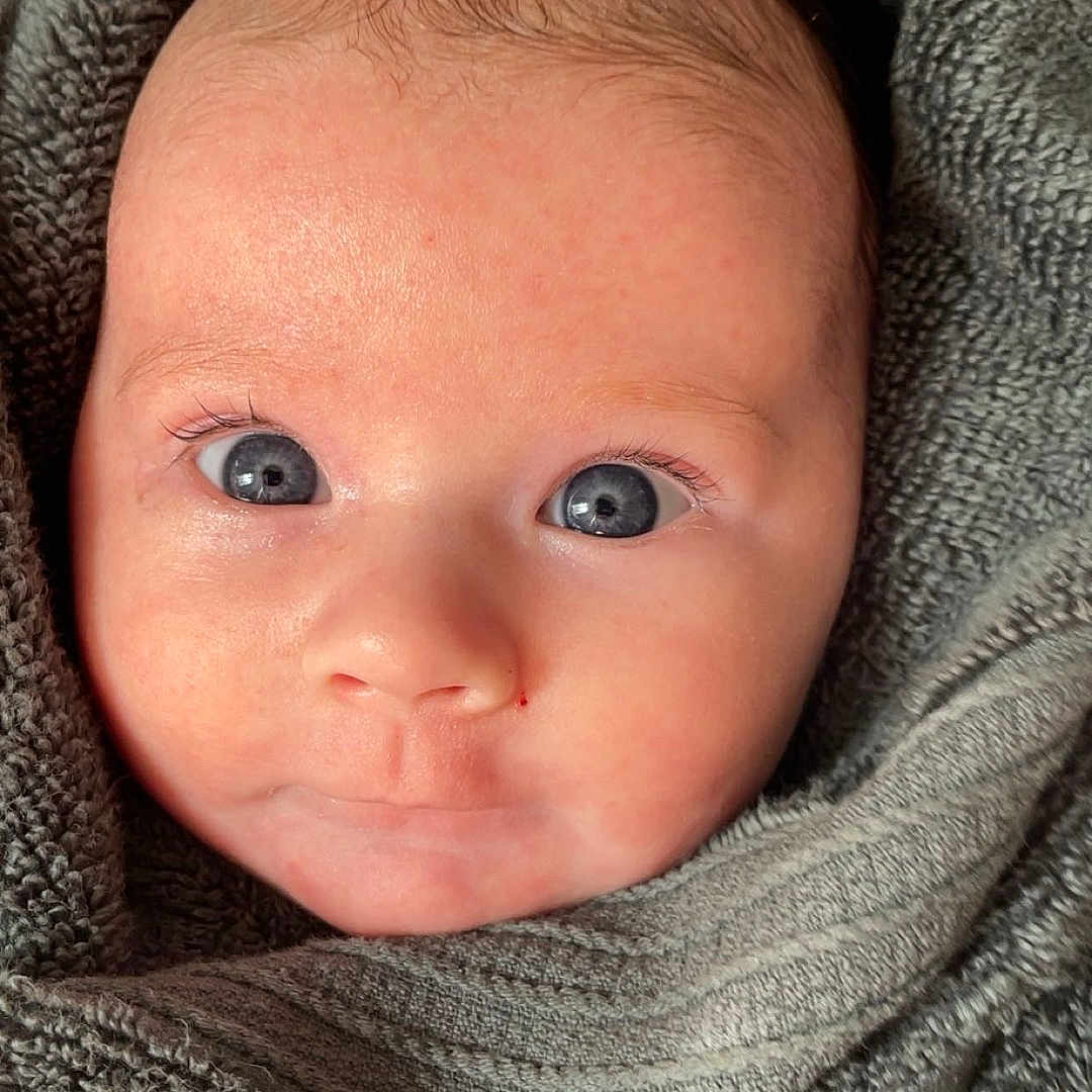 Aleia Lily joined the competition — help win amazing prizes! baby, blanket, bodypart, clothing, face, finger, hand, happy, hat, head, hood, hoodie, knitwear, newborn, person, photography, portrait, smile, sweater, sweatshirt