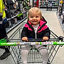 Scarlet-Rose is registered to the contest to win money with this photo: toddler, child, shopping_cart, store, aisle, kitchenware, books, jacket, leggings, smile, happy, blonde_hair, antimicrobial_handle, person, retail, shopping, indoor, holding, clothing, footwear