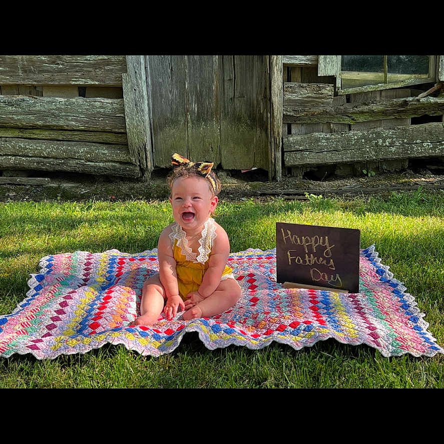 Remi is registered to the contest to win money with this photo: architecture, baby, backyard, blackboard, building, face, grass, head, lawn, nature, outdoors, person, photography, plant, portrait, quilt, shelter, sitting, summer, yard
