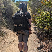 Freya is registered to the contest to win money with this photo: animal, backpack, dog, hat, hiking, leaves, nature, outdoor, path, person, plants, shadow, shoes, shorts, summer, sunny, tattoo, trail, trees, walking