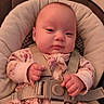 baby, child, infant, car_seat, safety_harness, pink_onesie, patterned_clothing, face, hands, cushion, seat, straps, indoor, portrait, cute, small_hands, young_child, resting, looking_at_camera, soft_lighting