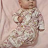 baby, infant, lying_down, floral_onesie, pink_blanket, soft_texture, cute, child, newborn, sleepwear, face, head, skin, hand, foot, expression, indoors, portrait, resting, comfort