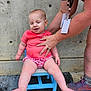 Rosaline is registered to the contest to win money with this photo: baby, child, person, pink_shirt, checkered_shorts, blue_chair, concrete_wall, adult_hand, supporting_hand, closed_eyes, sitting, outdoor, footwear, sneakers, skin, shorts, casual_clothing, fingers, legs, small_chair