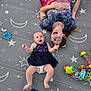 baby, woman, glasses, smile, toy, floor_mat, stars, moon, dress, diaper, colorful, playtime, joy, happy, child, person, laying_down, indoor, pattern, fun