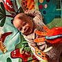 baby, smiling, play_mat, dinosaur, plush_toys, colorful, infant, happy, child, cute, indoors, toy, playtime, fabric, pattern, crawling, clothing, head, face, cheerful