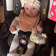 Delaney is registered to the contest to win money with this photo: baby, infant, child, car_seat, headband, bow, bib, onesie, booties, buckle, harness, blanket, pacifier, seat_pad, indoor, portrait, floor_tiles, polka_dot_fabric, soft_cloth, looking_at_camera