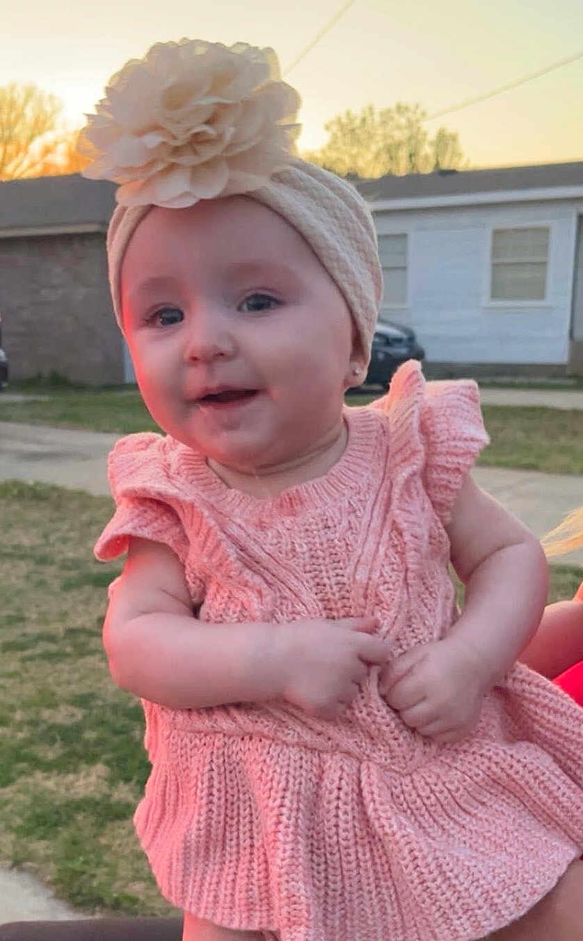 Delaney is registered to the contest to win money with this photo: baby, infant, girl, headband, flower_headband, pink_dress, knit_dress, smile, hands, portrait, outdoor, sunset, grass, yard, house, car, face, cute, adorable, child