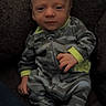 Buckley is registered to the contest to win money with this photo: baby, infant, camouflage, pajamas, clothing, face, person, cute, cozy, plush, furniture, indoor, newborn, portrait, child, small, hands, feet, sitting, expression