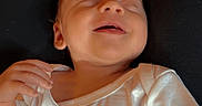 Buckley is registered to the contest to win money with this photo: baby, infant, smiling, eyes_closed, white_shirt, lying_down, hand, peaceful, cute, child, person, sleeping, portrait, indoors, soft_lighting, relaxed, young, toddler, clothing, skin