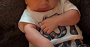 Buckley joined the competition — help win amazing prizes! baby, infant, child, person, couch, clothing, white_shirt, patterned_shorts, sitting, indoors, soft_texture, skin, face, head, hand, legs, footwear, curious, smile, relaxed