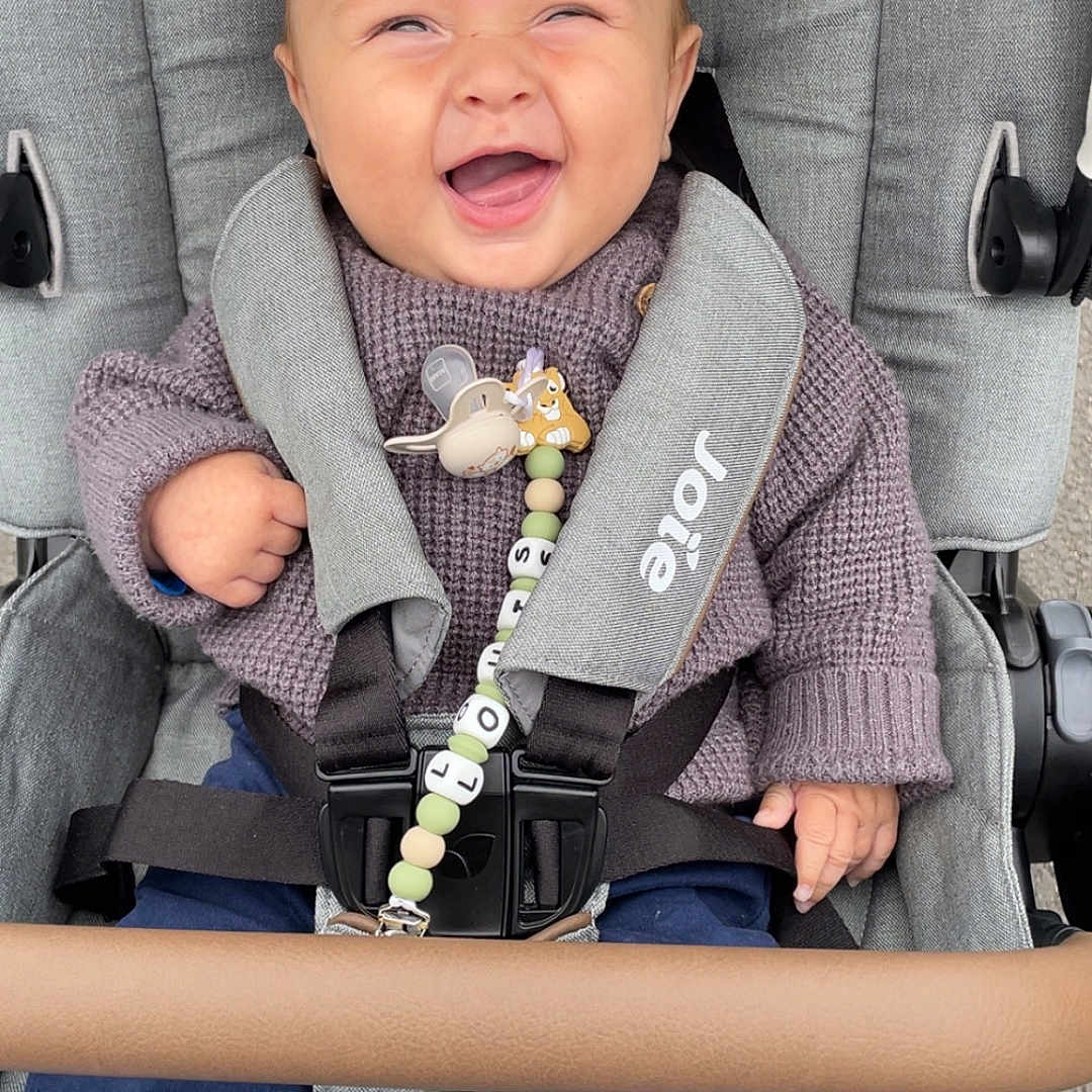 Louis a rejoint le concours — aidez-le/la à gagner de superbes lots ! baby, child, clip, clothing, comfort, fabric, footwear, hand, happy, head, outdoor, pacifier, pale_skin, person, seatbelt, sitting, smiling, stroller, sweater, toy