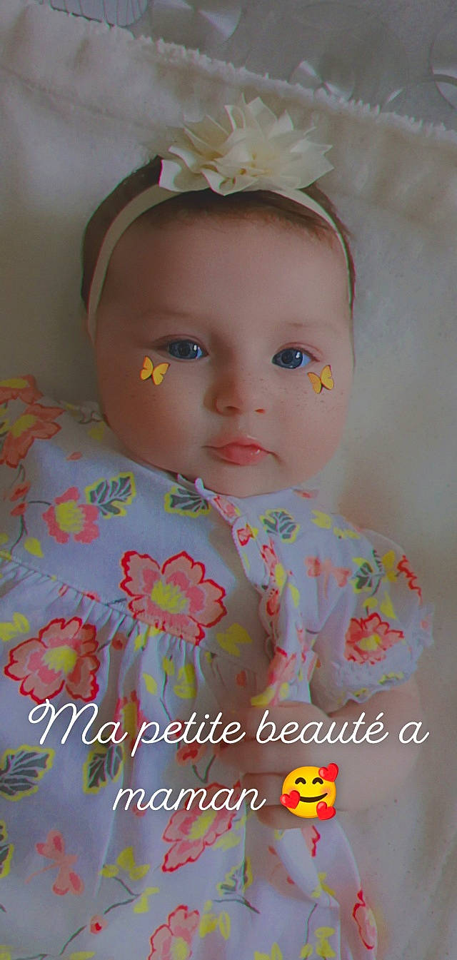 Maëlyne participe au concours pour gagner de l'argent avec cette photo : baby, baby_toddler_clothing, child, doll, eye, eyelash, hairstyle, happy, headgear, iris, lip, pattern, person, pink, skin, sleeve, textile, toddler, toy, white