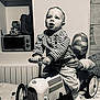 toddler, child, toy_car, vintage_toy, striped_shirt, hand, balloon, party, celebration, indoors, radiator, microwave, table, confetti, sock, curious, support, furniture, monochrome, portrait