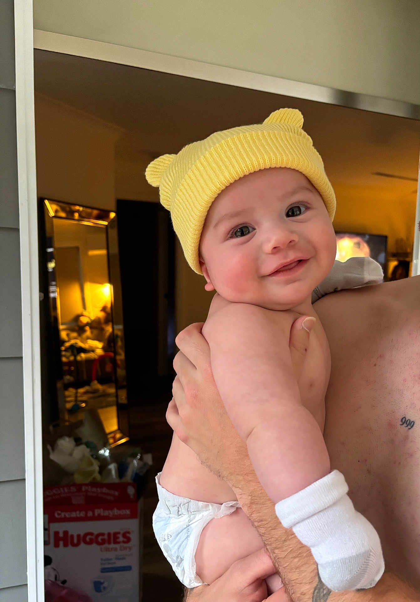 Keanu joined the competition — help win amazing prizes! baby, infant, smile, yellow_hat, diaper, white_sock, arm, hand, mirror, room, clutter, box, huggies, reflection, indoor, person, holding, cute, happy, child