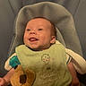 Bryar is registered to the contest to win money with this photo: baby, infant, smiling, tongue_out, bib, plush_toy, pacifier, baby_seat, cushion, green_bib, clothing, happy, cute, child, indoor, portrait, young_child, comfort, toy, playful