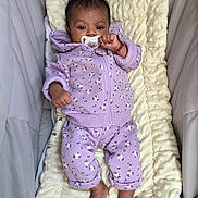 Ysanah a rejoint le concours — aidez-le/la à gagner de superbes lots ! baby, pacifier, purple_clothing, floral_pattern, blanket, soft_texture, infant, lying_down, bracelet, cute_outfit, baby_clothes, indoor, comfortable, small_feet, child, newborn, portrait, resting, baby_bedding, calm