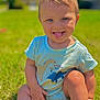 child, toddler, blue_eyes, tongue_out, onesie, dinosaur_print, grass, outdoor, sunny_day, smiling, cute, baby, sitting, playful, innocence, portrait, greenery, summer, childhood, happy