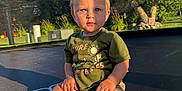 Amari joined the competition — help win amazing prizes! toddler, child, blue_eyes, green_shirt, shorts, trampoline, outdoor, sunlight, nature, trees, grass, garden, sitting, barefoot, curious, portrait, daylight, play, young_child, summer