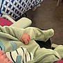 baby, infant, onesie, clothing, hand, foot, patterned_bedding, indoor, soft_fabric, resting, cute, animal_applique, furniture, comfort, closeup, cozy, newborn, child, person, warm