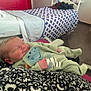 Mylan a rejoint le concours — aidez-le/la à gagner de superbes lots ! newborn, baby, sleeping, onesie, green_clothing, blanket, hospital_bed, red_cabinet, indoor, infant, peaceful, smiling, face, hand, footwear, furniture, wall, room, person, portrait