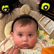 Gabrielle participe au concours pour gagner de l'argent avec cette photo : baby, child, headband, face, rosy_cheeks, blanket, hand, patterned_blanket, indoor, seated, toy, soft_toys, cute, infant, clothing, person, closeup, expression, gaze, accessory