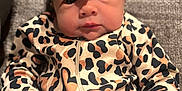 Oaklee is registered to the contest to win money with this photo: baby, infant, face, headband, bow, leopard_print, clothing, onesie, fist, hand, couch, fabric, portrait, indoor, skin, cute, person, young, seated, expression